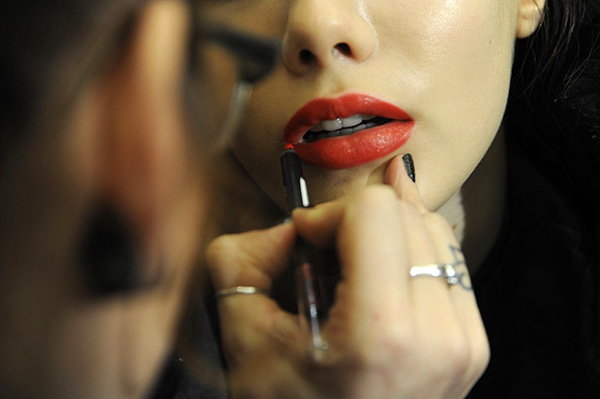 Makeup artist applying red lipstick